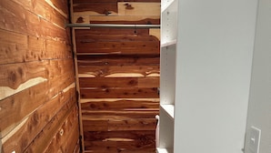 A narrow hallway with wooden paneling on one side and white shelving units on the other.