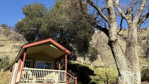 A red cabin with a balcony, surrounded by trees and a hillside. - Cottage, Sleeps 4 - Scenic Cottage, 1 Bedroom, Sleeps 4 (Winters)