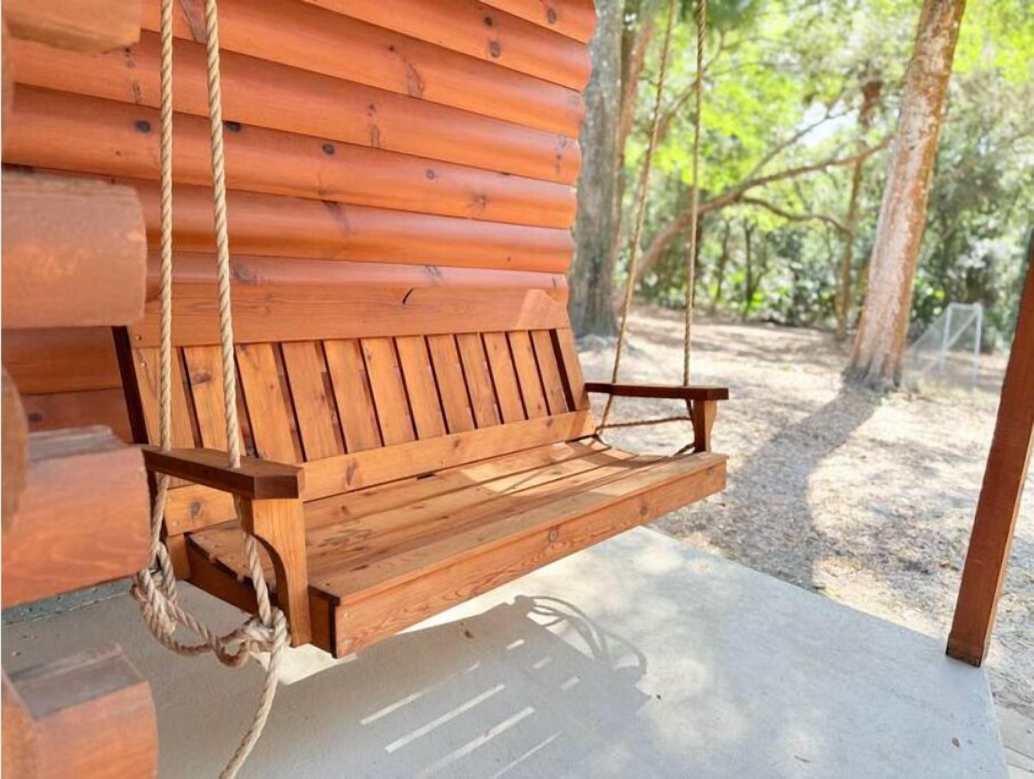 Une balançoire en bois fixée à une structure de cabane en rondins.