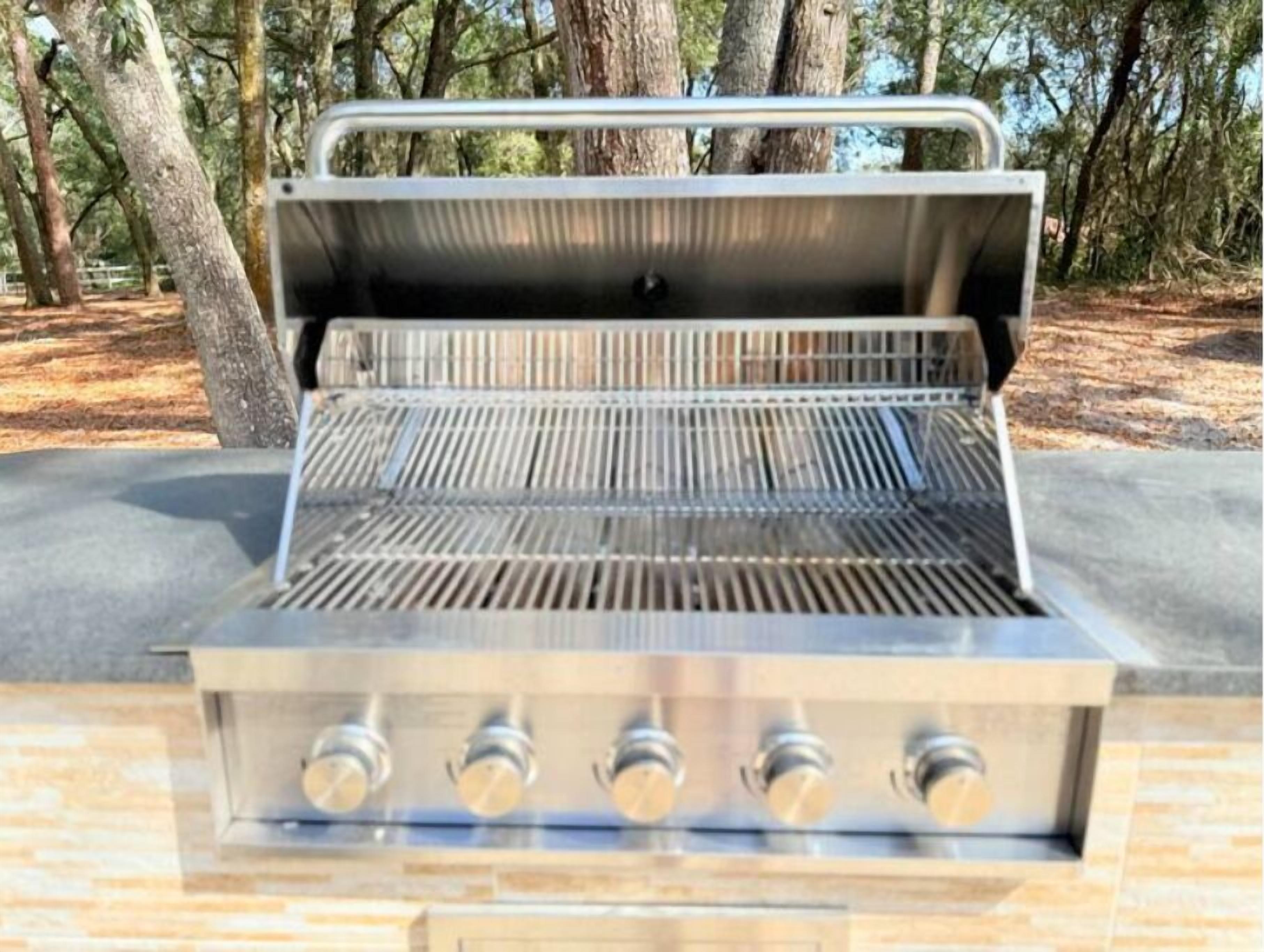 A stainless steel grill with a flat top and four burners.
