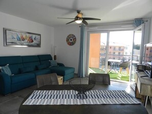 Relax in this stylish living room with a sofa, coffee table, and ceiling fan. Enjoy the view from the balcony through the large window.