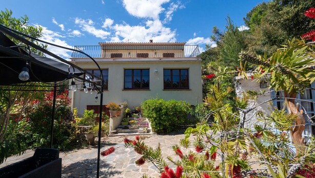 A two-story building with a balcony, stone pathway, and potted plants. - T4 , Jardin arboré et plages à moins de 5 min à pieds (BORMES LES MIMOSAS)