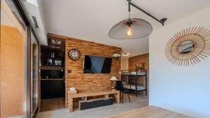 Ein modernes Wohnzimmer mit Holzwand, Flachbildfernseher, Esstisch und einer Bank.