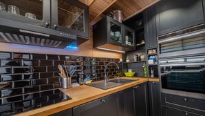 Eine moderne Küche mit schwarzen Schränken, einer Holz Arbeitsplatte und einer Edelstahl-Dunstabzugshaube.