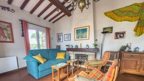 A living room with a blue sofa, wooden armchairs, a fireplace, and various wall art.