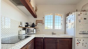 La cuisine est équipée d’un four à micro-ondes, d’un grille-pain et d’un réfrigérateur. Une fenêtre offre une vue sur l’extérieur.