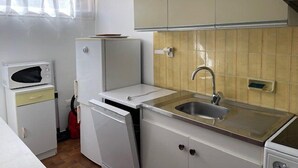 Une cuisine compacte équipée d’un four à micro-ondes, d’un réfrigérateur, d’un évier et de placards.