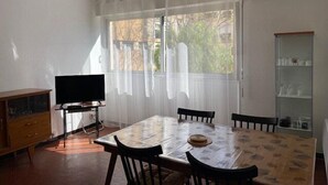 Un espace repas comprenant une table, des chaises, un téléviseur et un meuble.