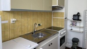 Une cuisine de taille réduite, équipée d’un évier, d’une cuisinière et d’un petit plan de travail.