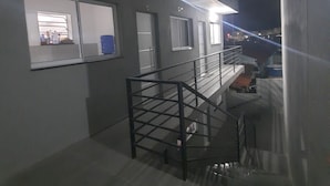 En modern byggnad med en trappa som leder upp till en övre våning, ett fönster med utsikt över interiören och en dörr med ett nummer ovanför.