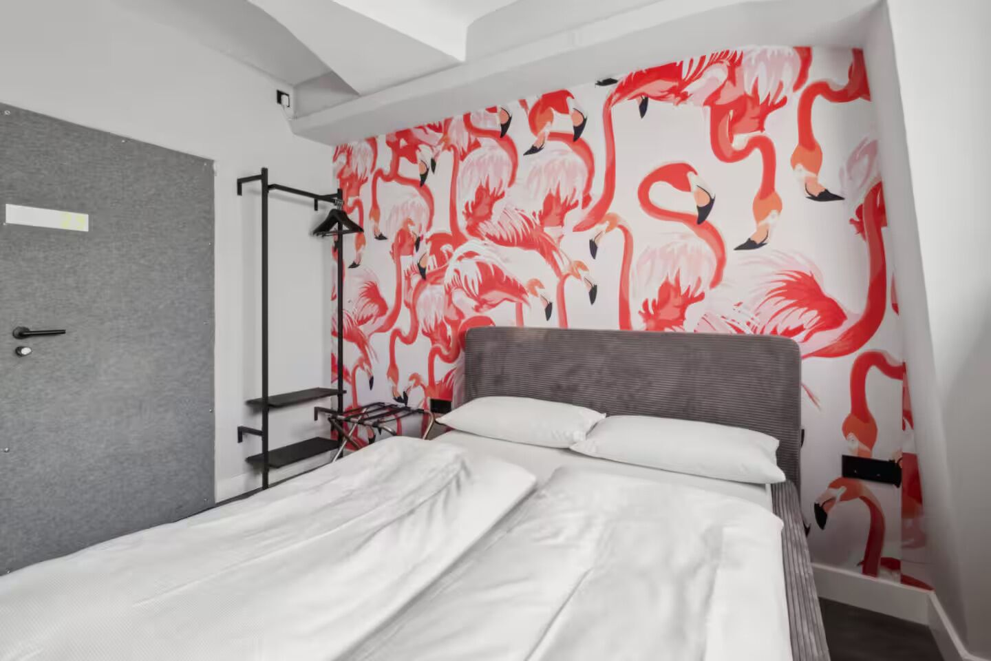 A bedroom with a bed, a wardrobe, and a wall with a flamingo pattern.