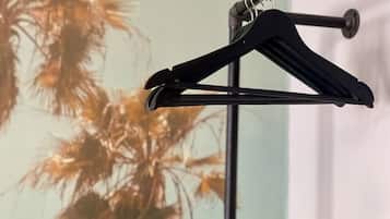 A black coat hanger against a wall with a palm tree painting.