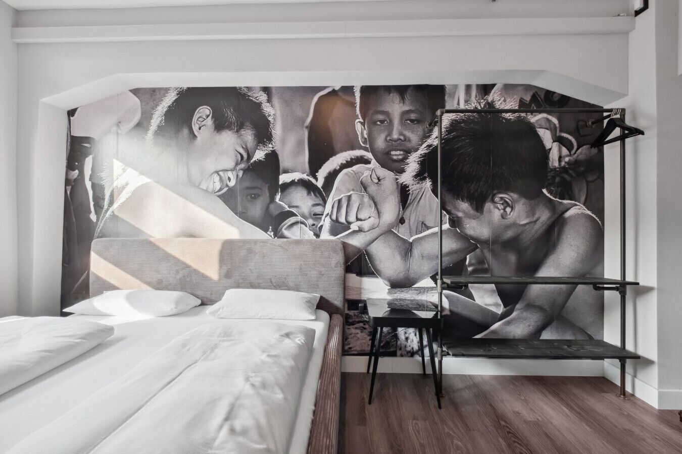 A bedroom with a bed, a wooden floor, and a large abstract painting on the wall.