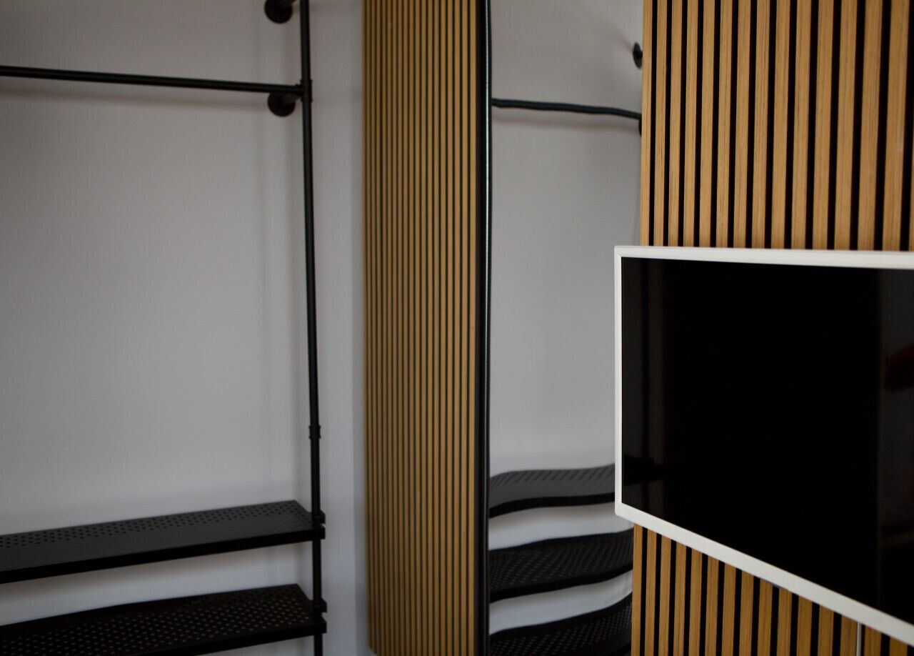Una habitación con una cama, un televisor montado en la pared y un diseño de paneles de madera.