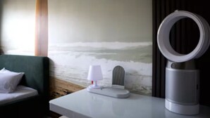 A room with a bed, a lamp, a ring light, and a wall with a textured design. - The Room 44 (Hamburg)
