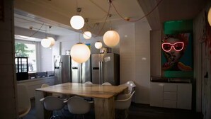 A modern kitchen with a wooden dining table, white chairs, and stainless steel appliances. - The Room 44 (Hamburg)