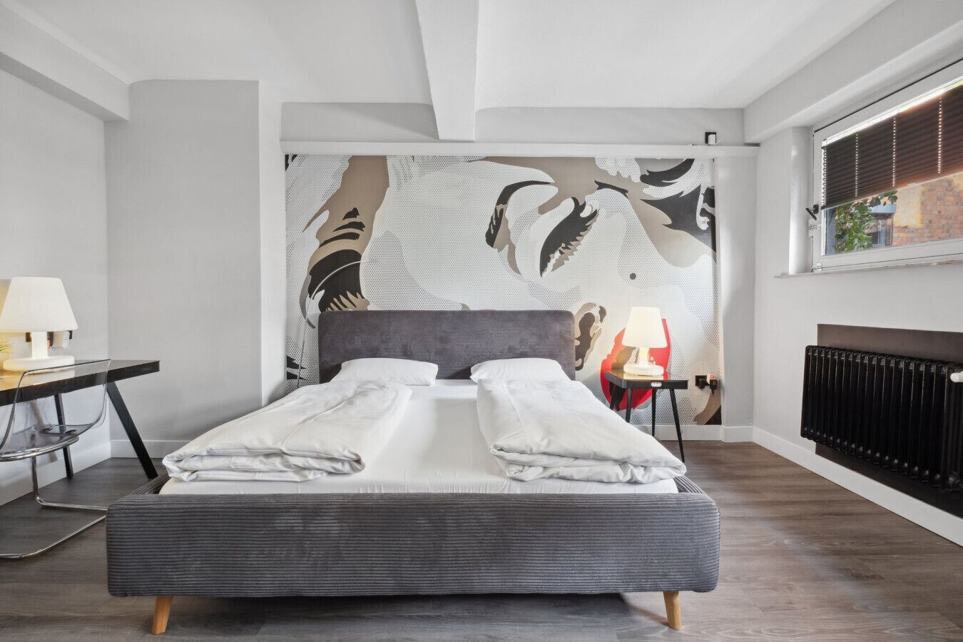 Un dormitorio moderno con una cama grande, un escritorio y un radiador.