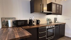 A modern kitchen with dark cabinetry, a wooden countertop, a built-in oven, and a coffee maker.