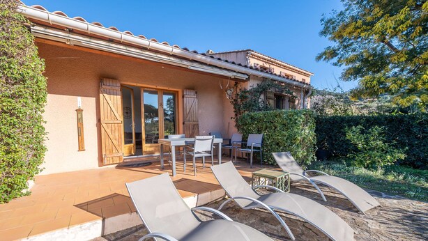 A building with a tiled roof, a patio with lounge chairs, and a wooden door. - Maison, climatisée plage St Clair et commerces (LE LAVANDOU)