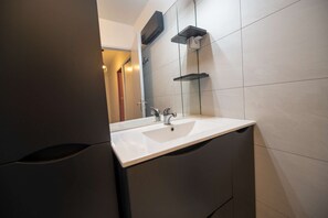 A modern bathroom with a white sink, a mirror, and a towel rack. - Maison, climatisée plage St Clair et commerces (LE LAVANDOU)