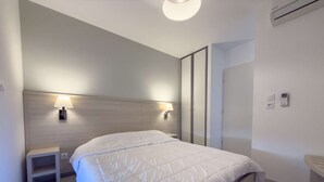 Une chambre d’hôtel moderne avec un grand lit, des lampes de chevet, une table de chevet, une armoire et un petit lavabo.