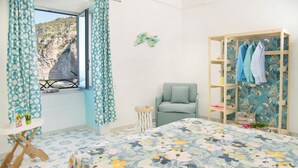 Une chambre à coucher comprenant un lit, une chaise, une armoire en bois, une fenêtre avec des rideaux et un élément de décoration murale.