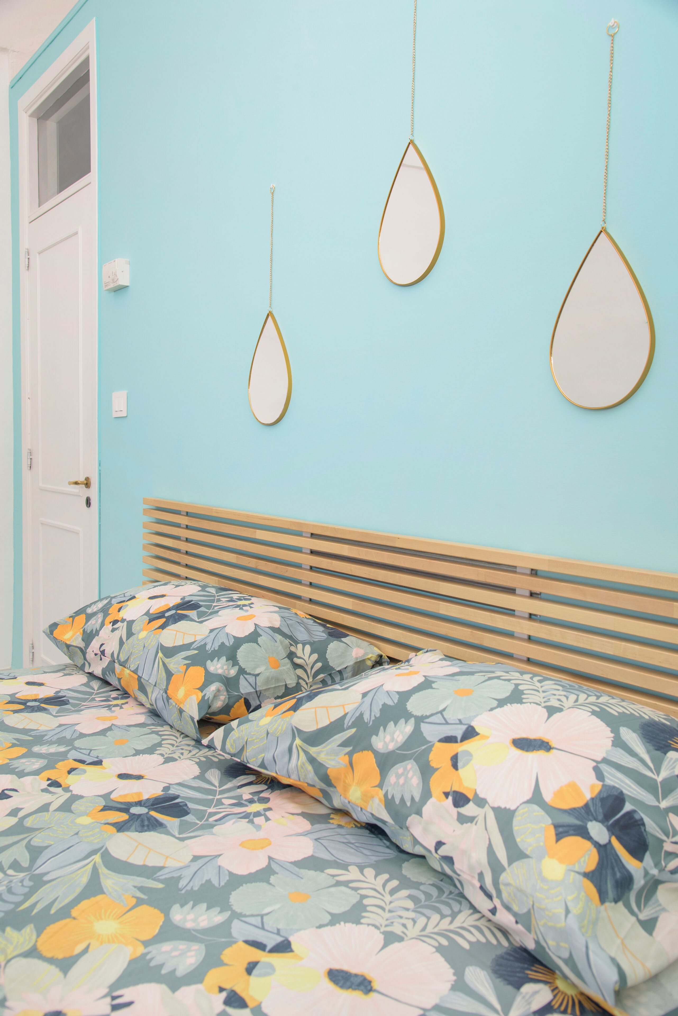A bedroom with a bed, floral bedding, and wall-mounted mirrors.
