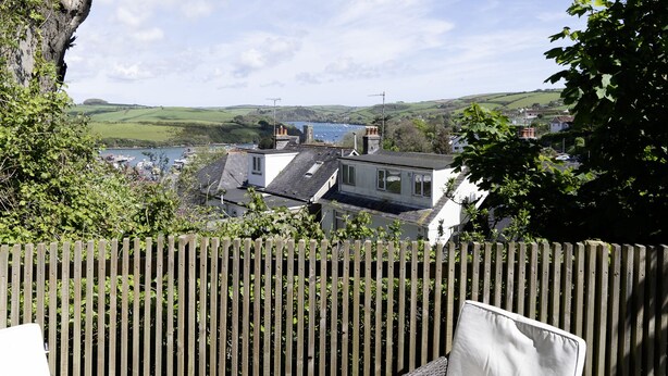 A wooden deck with wicker furniture, a laptop, and a table with food and drinks. - The Hideout-Boutique Cabin, Estuary View & Parking (Salcombe)