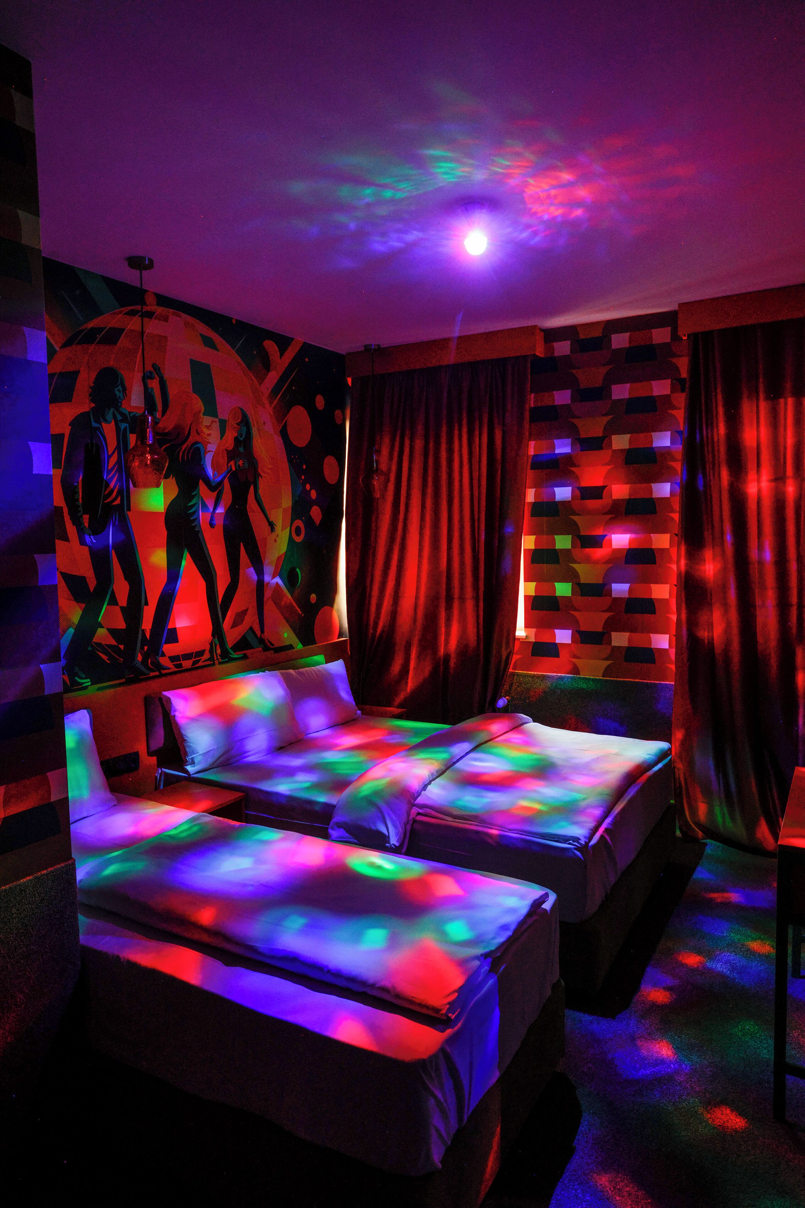 A room with two beds, a mural on the wall, and a ceiling light.