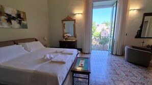 A hotel room with a large bed, a small table, a mirror, and a view of the outside. - BUILDING COSI-FORINA (Morciano di Leuca)