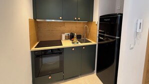 A compact kitchen with dark cabinets, a built-in oven, a sink, and a black refrigerator. - Superb 6-person T3 apartment close to the slopes (Péone)