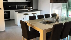 Una cocina moderna con gabinetes blancos, una encimera negra y una isla central con taburetes.