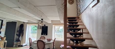 A dining area with a round table, chairs, and a staircase.