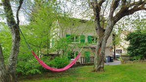 Una hamaca entre árboles en un área verde, con un edificio al fondo.