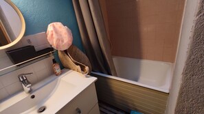 Un baño con lavabo, espejo y zona de ducha.