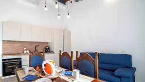Eine moderne Küche mit Esstisch für zwei Personen, einem blauen Sofa und einer Holzzahl.