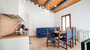 Eine kompakte Küche mit modernen Geräten, ein Essbereich mit Holzkästen und ein blaues Sofa.