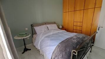 A bedroom with a bed, a bedside table, a lamp, and a wardrobe.