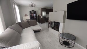 Ein modernes Wohnzimmer mit einem Ecksofa, einem Kamin und einem Essbereich im Hintergrund.
