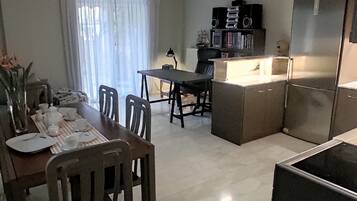 Een moderne keuken met een koelkast, een eettafel met stoelen en een kroonluchter.