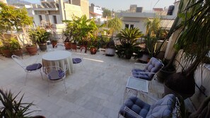 Relax in a serene rooftop setting with a round table and four chairs surrounded by lush greenery.