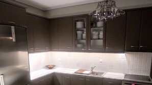 Eine moderne Küche mit dunklen Schränken, einem Edelstahl-Kühlschrank, einer Spüle und einem eingebauten Backofen.