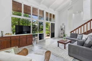A spacious living room with a large TV, grey sofa, and a wooden cabinet.
