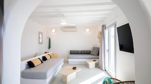 A modern living room with a sofa, a small table, a TV, and a window.