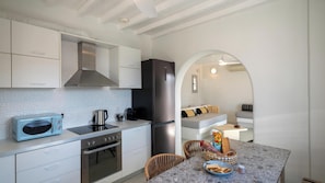 A compact kitchen with a microwave, stove, and refrigerator, leading to a dining area with a table and chairs.
