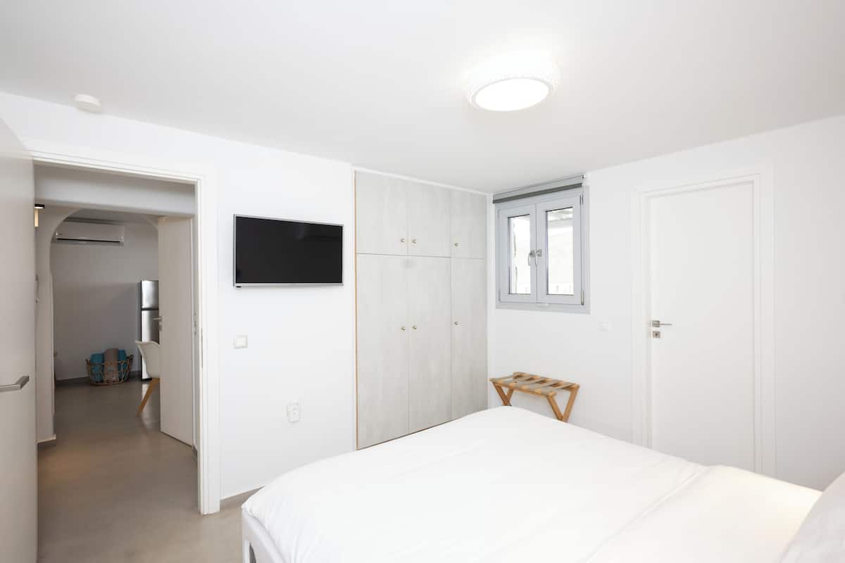 A bedroom with a bed, wardrobe, and a television on the wall.