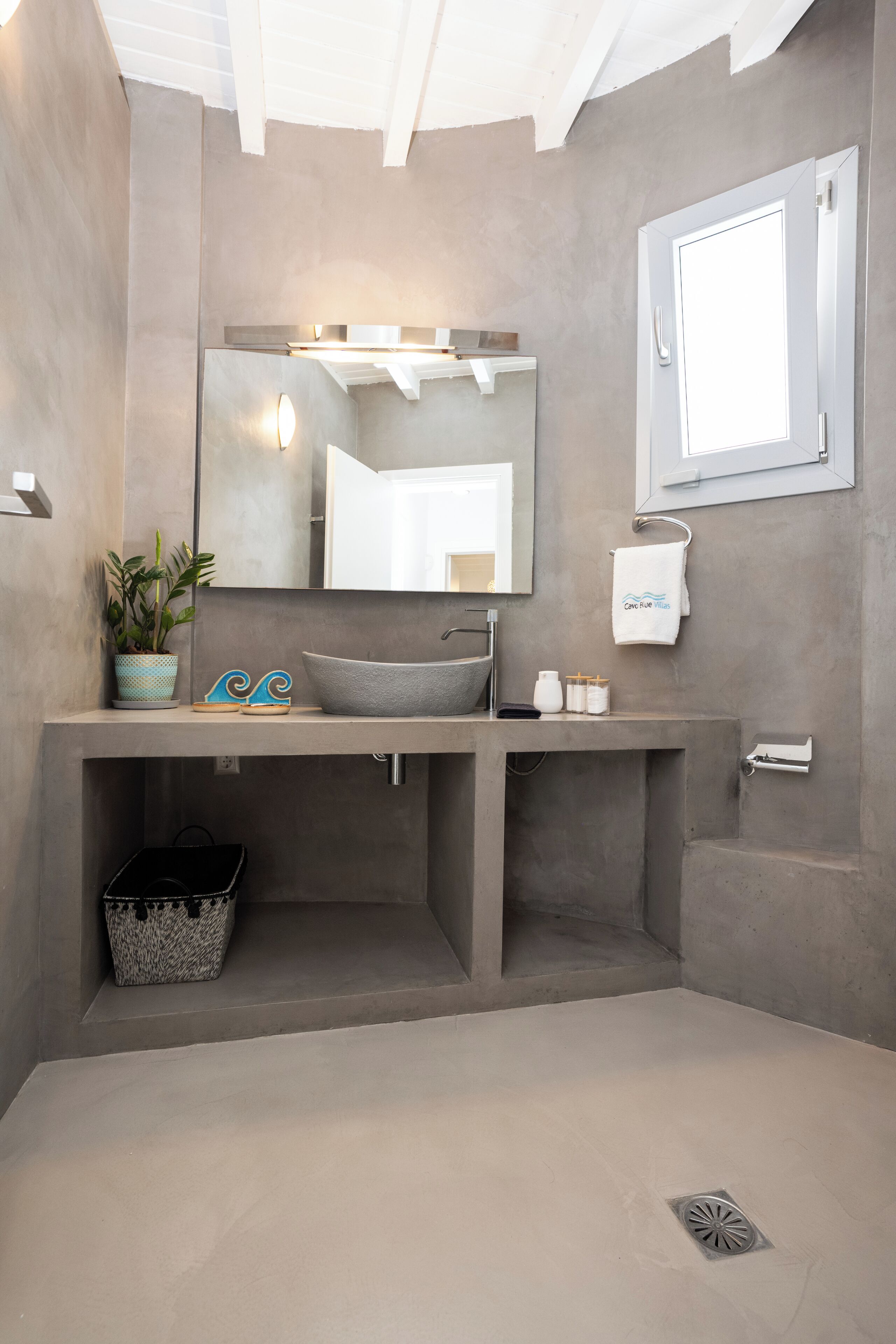 A modern bathroom with a large mirror, a vessel sink, a towel rack, and a potted plant.