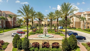 A resort with a central fountain, palm trees, and a parking area. - Comfortable 3BR Near Convention Center Epic Park (Orlando)