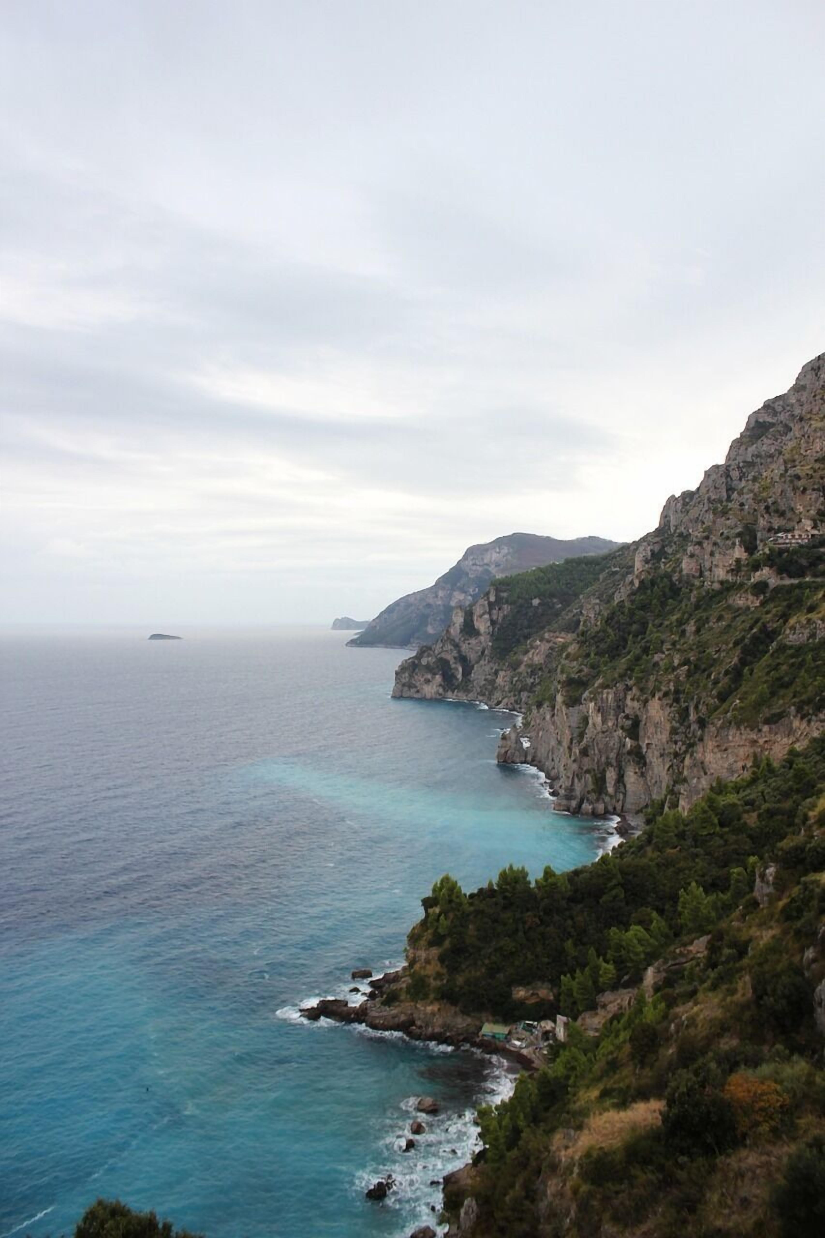 A coastal landscape with rocky cliffs and a clear view of the sea.