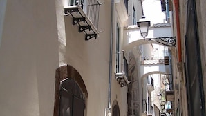 A narrow alleyway with buildings on either side, featuring balconies, arched doorways, and hanging street lamps. - L'Incanto House (Salerno)
